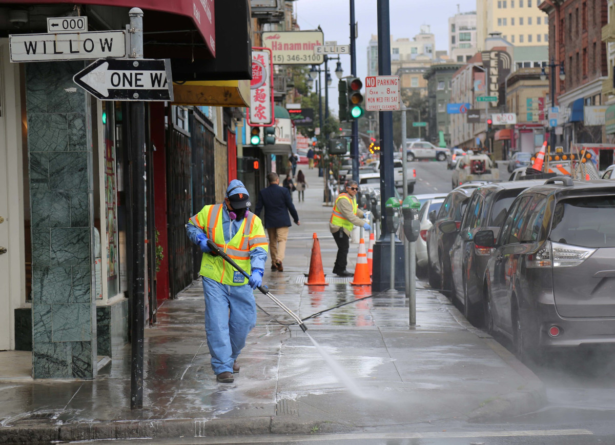 A worker cleaning the street with a high pressure hose